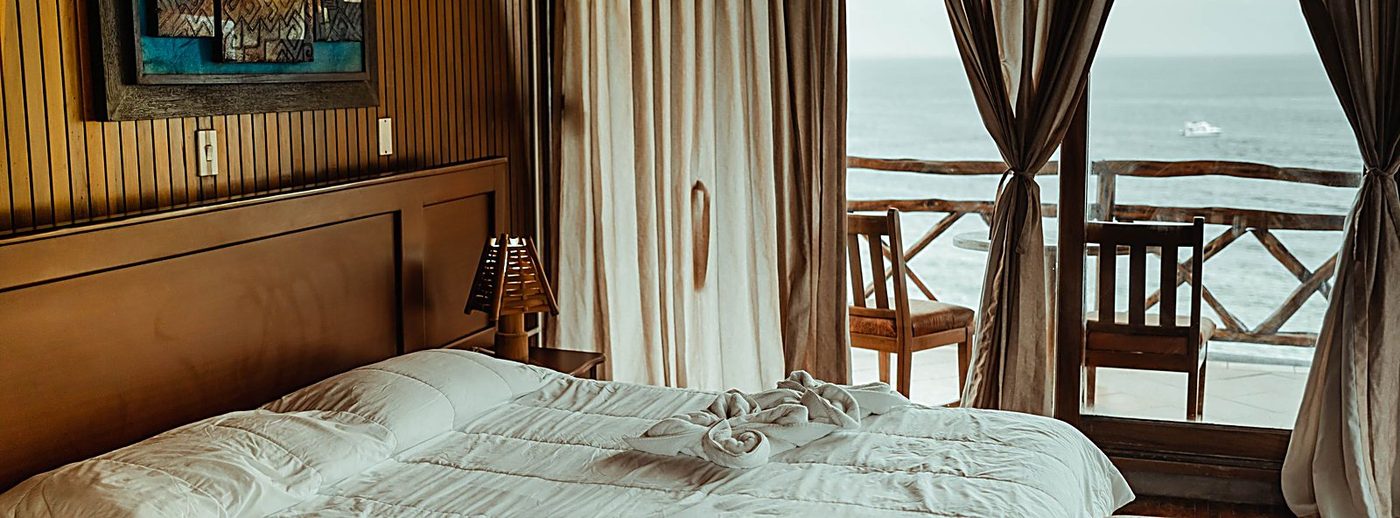 Cameră de hotel în amurg, cu balcon deschis și vedere la mare