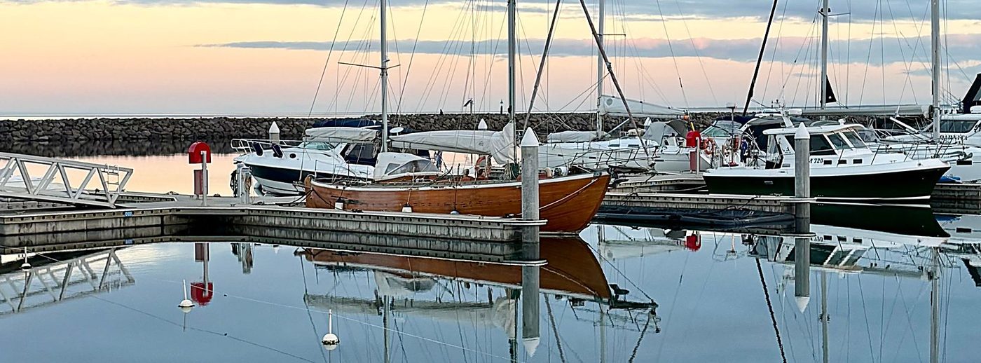 Bărci la ponton, în amurg, oglindite în apa liniștită
