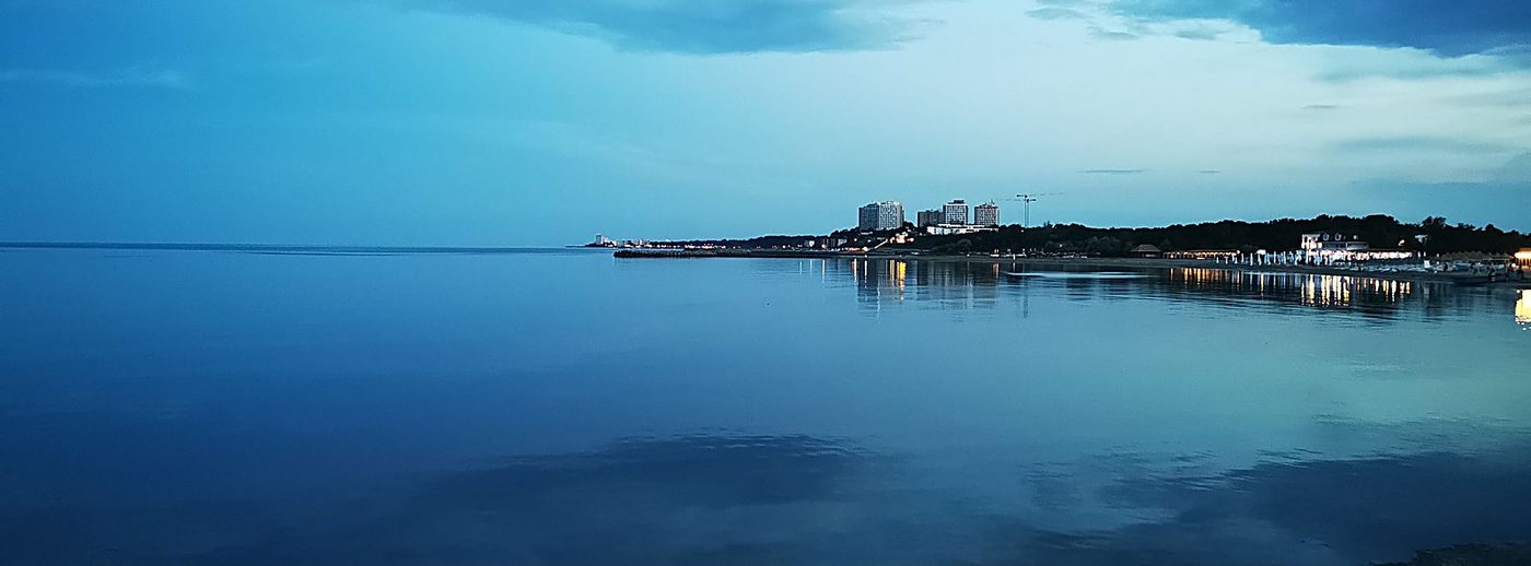Marea la asfințit, cu luminile stațiunii pe linia orizontului